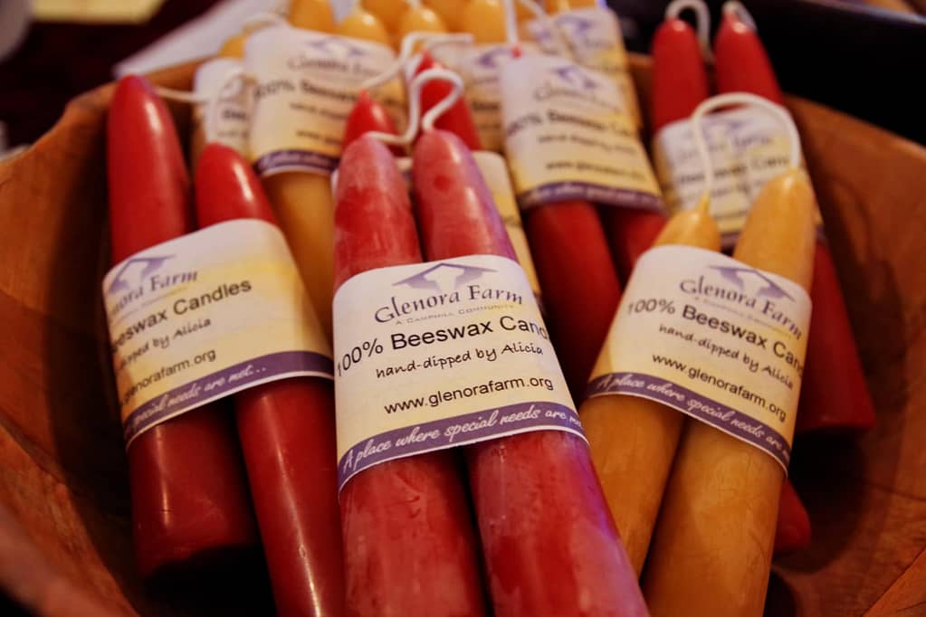 A stack of hand-dipped beeswax candles is displayed, with labels wrapped around each pair.